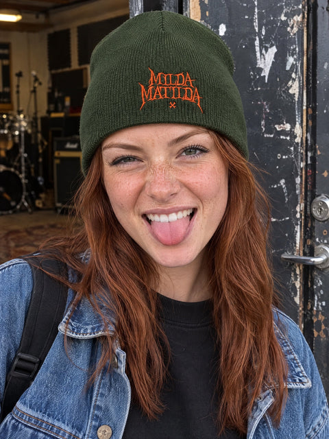 Milda Matilda på olivgrön Hatitude Beanie, buren av en yngre vuxen.